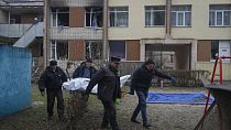 Des employés municipaux transportent des corps de victimes d'un accident d'hélicoptère depuis un jardin d'enfants à Brovary, près de Kyiv