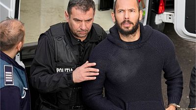Police officers escort Andrew Tate, right, handcuffed to his brother Tristan Tate, to the Court of Appeal in Bucharest, Romania