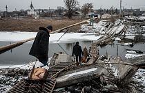 Residente caminham em ponte destruída na região de Bakhmut
