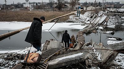 Residente caminham em ponte destruída na região de Bakhmut