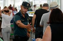 A civil guard officer gestures as passengers pass the security control at the Barcelona airport in Prat Llobregat, Spain, Aug. 14, 2017. 