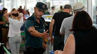 A civil guard officer gestures as passengers pass the security control at the Barcelona airport in Prat Llobregat, Spain, Aug. 14, 2017.