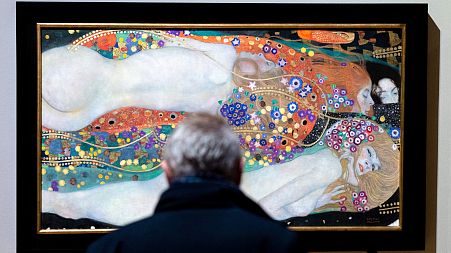 A visitor looks at the painting 'Water Serpents II'