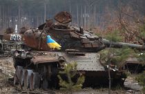 دبابة روسية محترقة وعليها رسم لحمامة تحمل لوني العالم الأوكراني بقرية دميتريفكا في محيط كييف