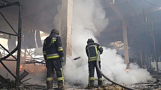 Ukrainian firefighters spraying water inside the burnt down shopping centre in Kherson. 