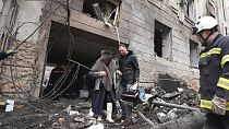 Un homme aide une habitante de Kharkik à sortir de son immeuble touché par une frappe russe, 5 février 2023