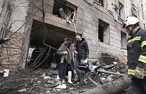 Un homme aide une habitante de Kharkik à sortir de son immeuble touché par une frappe russe, 5 février 2023