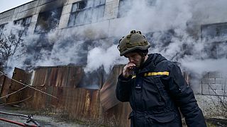 Emergency workers saw a tree in front of a residential building which was hit by a Russian rocket at the city center of Kharkiv, Ukraine, Sunday, Feb. 5, 2023. 