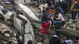 Personas y equipos de emergencia rescatan a una persona en camilla de un edificio derrumbado en Adana, Turquía, el lunes 6 de febrero de 2023.