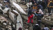 Personas y equipos de emergencia rescatan a una persona en camilla de un edificio derrumbado en Adana, Turquía, el lunes 6 de febrero de 2023.