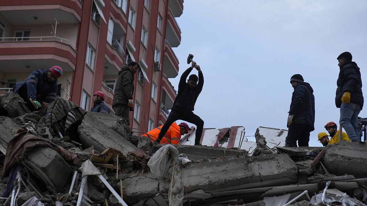People and emergency teams search for people in a destroyed building in Adana, Turkey.