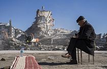 Ein Mann im südtürkischen Nurdagi sitzt auf einem Stuhl. Hinter ihm sind die Gebäude wie Kartenhäuser zusammengefallen.
