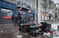 People pass by working generators during a power outage in Kyiv, Ukraine, Monday, Feb. 6, 2023.