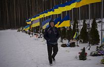 Homem passeia pela Avenida dos Heróis, no cemitério de Irpin, Ucrânia