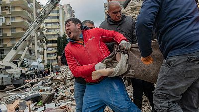 A rescuer reacts as he carries a body found in the rubble in Adana on February 6, 2023, after a 7.8-magnitude earthquake struck the country's south-east.