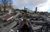 A woman sits on the rubble as emergency rescue teams search for people under the remains of destroyed buildings in the outskirts of Osmaniye in southern Turkey.