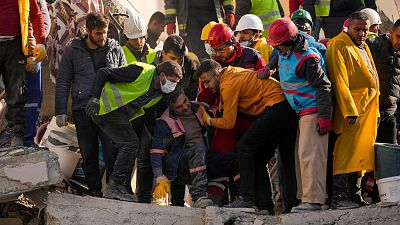 An emergency rescue team member is comforted by teammates after they found two bodies in a destroyed building in Adana, Turkey.