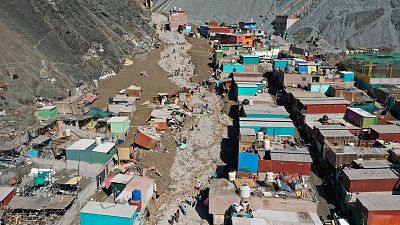 Residents walk on a street covered with debris caused by a landslide, in Camana, Peru, Tuesday.
