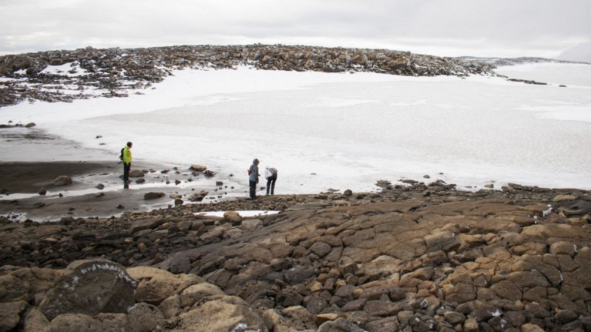   ينظر الناس إلى الثلج في النهر الجليدي القديم بعد الكشف عن نصب تذكاري في موقع Okjokull، غرب أيسلندا- 18 أغسطس 2019.