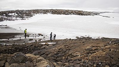   ينظر الناس إلى الثلج في النهر الجليدي القديم بعد الكشف عن نصب تذكاري في موقع Okjokull، غرب أيسلندا- 18 أغسطس 2019.