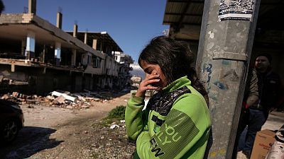 A girl stands next to destroyed buildings in Antakya, southern Turkey, Wednesday, Feb. 8, 2023.