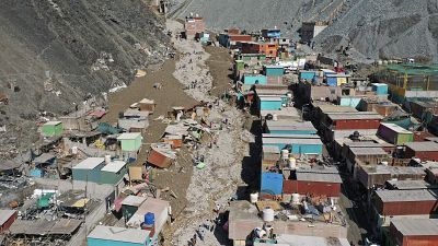 سكان يسيرون في شارع مليء بالحطام الناجم عن انهيار أرضي، في كامانا، بيرو، الثلاثاء 7 فبراير/شباط 2023.