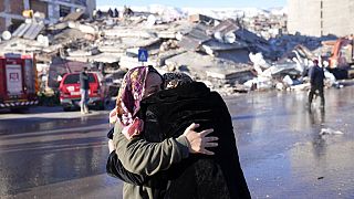 Two women hug each other in front of a destroyed building in Kahramanmaras, southern Turkey