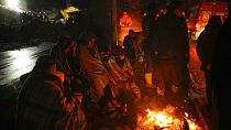 Menschen wärmen sich an einem Feuer, während Rettungsteams in Elbistan in der Südtürkei nach Menschen suchen