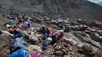A földcsuszamlás következtében megsemmisült otthonukból kimentett és még használható holmik között ül egy család a perui Camanában 2023. február 7-én.