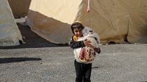 A Syrian child carries bread at a make-shift shelter for people who were left homeless, near the rebel-held town of Jindayris on February 9, 2023.