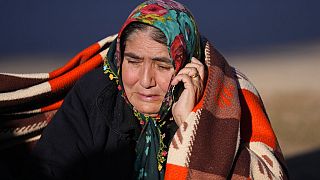 A woman speaks on her cellphone as rescuers search a destroyed building in Gaziantep, southeastern Turkey, Thursday, Feb. 9, 2023