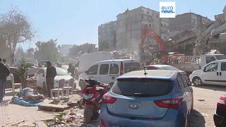 Bypassers onlook at the debris and rubble in the Turkish city of Antakya 