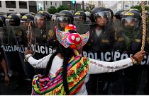 متظاهرة مناهضة للحكومة تقف أمام عناصر الشرطة في ليما 