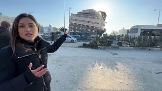 Корреспондент Euronews Анелиз Боржес на фоне разрушенной больницы в Антакье