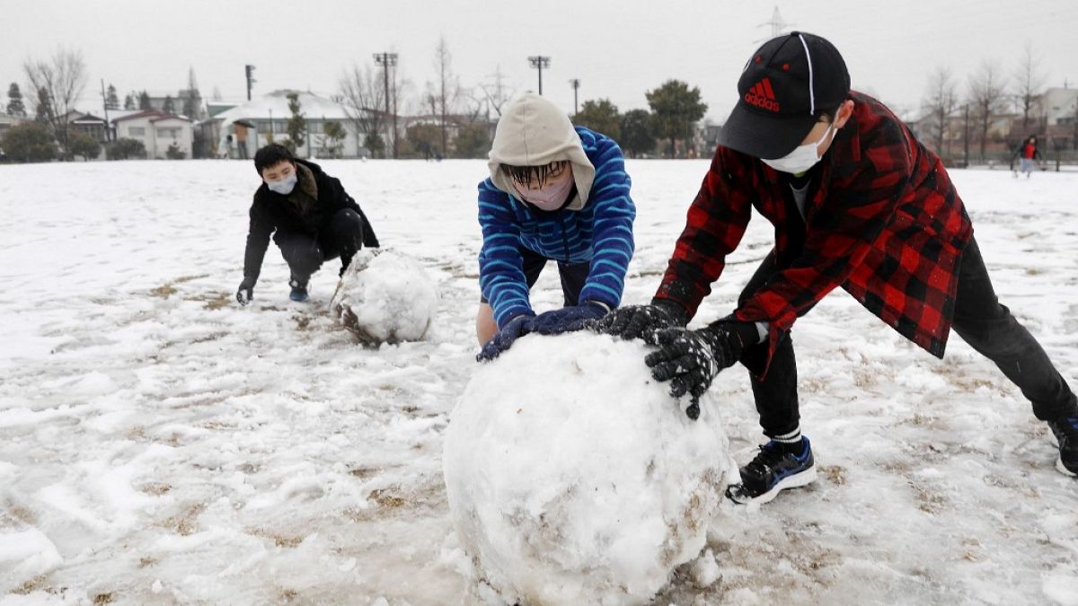 يحاول الأطفال صنع رجل ثلج بعد تساقط الثلج عبر أجزاء من منطقة العاصمة طوكيو- 10 فبراير 2023.