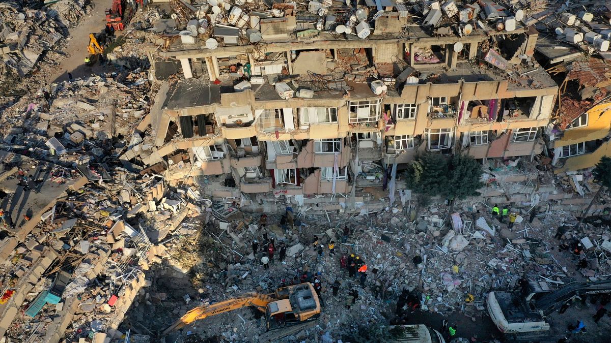 Rescue teams search for people as an excavator removes debris from a destroyed building in Antakya, southeastern Turkey, Friday, Feb. 10, 2023