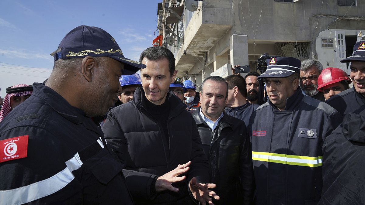 Syrian President Bashar Assad, second left, speaks with an Algerian rescue team at the site of destroyed 