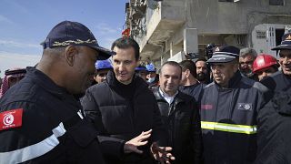 Syrian President Bashar Assad, second left, speaks with an Algerian rescue team at the site of destroyed 