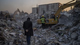 Um homem fica em cima dos escombros da sua casa, destruída durante um terramoto em Antakya, no sudeste da Turquia
