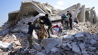 سوريون ينتشلون بعض المقتنيات من بيتهم الذي دمره الزلزال في الأتارب شمال غربي سوريا