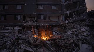 Турецкая семья греется у костра на развалинах своего дома