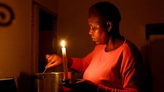 A woman cooks by a candlelight during one of the frequent power outages from utility Eskom, in Soweto, South Africa. 