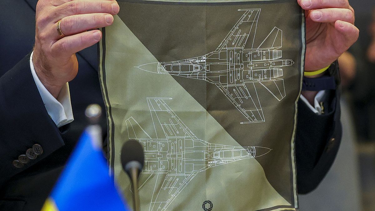 وزير الدفاع الأوكراني أوليكسي ريزنيكوف يعرض منديلًا عليه صورة طائرة مقاتلة كأولوية تحتاجها كييف قبل اجتماع وزراء الناتو في بروكسل. 2023/02/14
