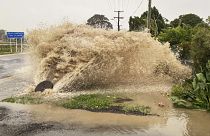 Water gushes from a storm drain access port on a street in Te Awanga, southeast of Auckland, New Zealand.