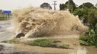 Water gushes from a storm drain access port on a street in Te Awanga, southeast of Auckland, New Zealand.