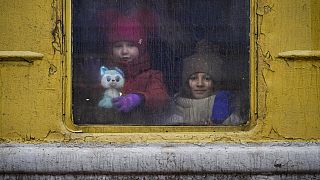 Children look out of the window of an unheated Lviv-bound train.