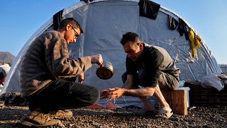 شاب يساعد والده على غسل يديه في مدينة اسكندرون التي ضربها الزلزال. 2023/02/14