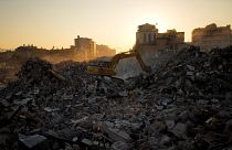 Ein Bagger gräbt sich durch die Trümmer zerstörter Gebäude in Iskenderun im Süden der Türkei