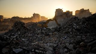 Ein Bagger gräbt sich durch die Trümmer zerstörter Gebäude in Iskenderun im Süden der Türkei