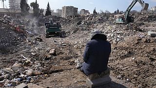 A man watches excavators remove rubble from his building in Kahramanmaras city, southern Turkey, Wednesday, Feb. 15, 2023.